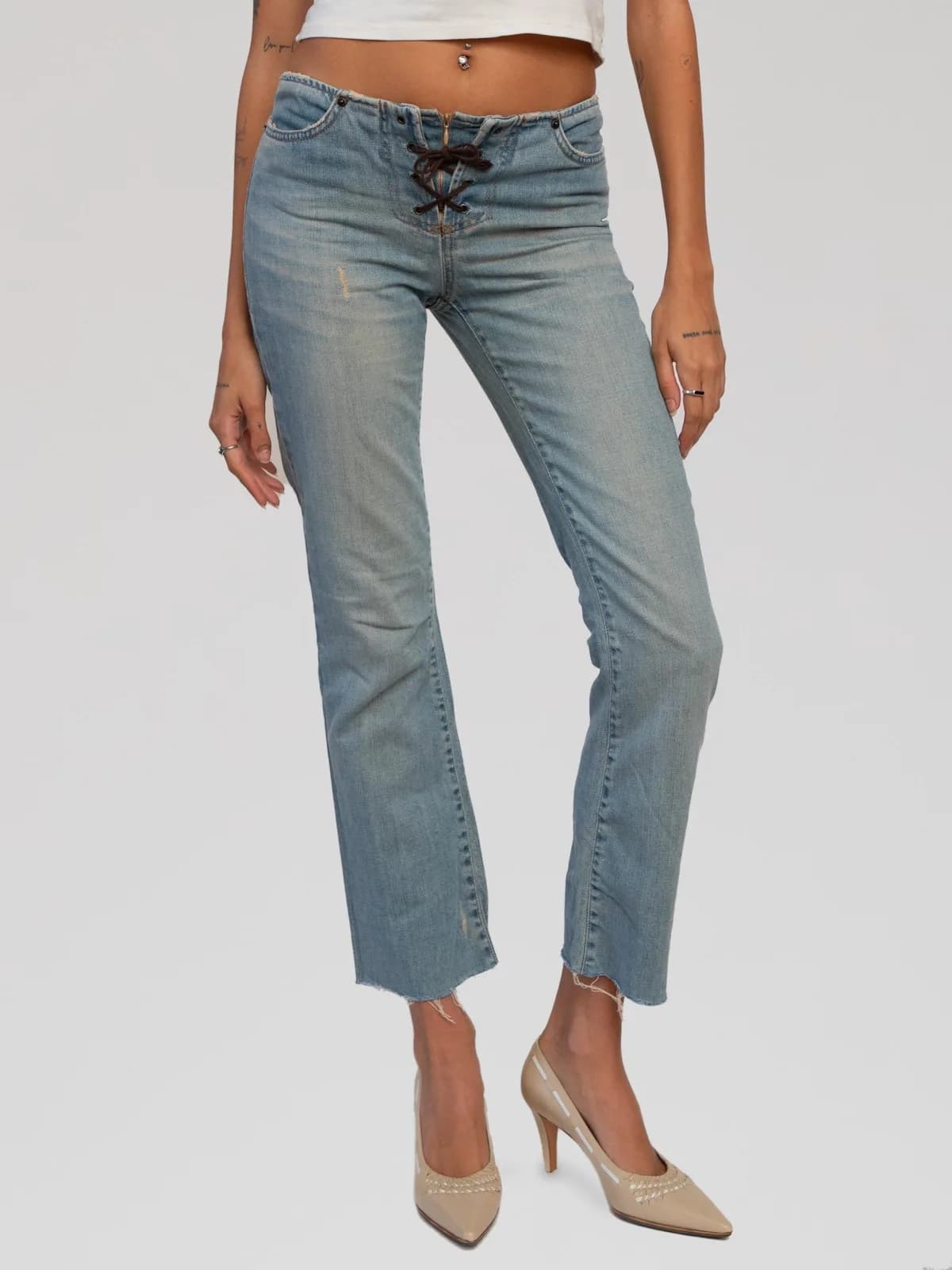 Vintage D&G Dolce & Gabbana light-wash denim straight-leg jeans featuring a low-rise waist with a dark brown lace-up fly closure, classic five-pocket styling with signature arch stitching on the back pockets, a raw-edge frayed waistband and hems, and an Ittierre tag indicating made in Italy. - Image 1