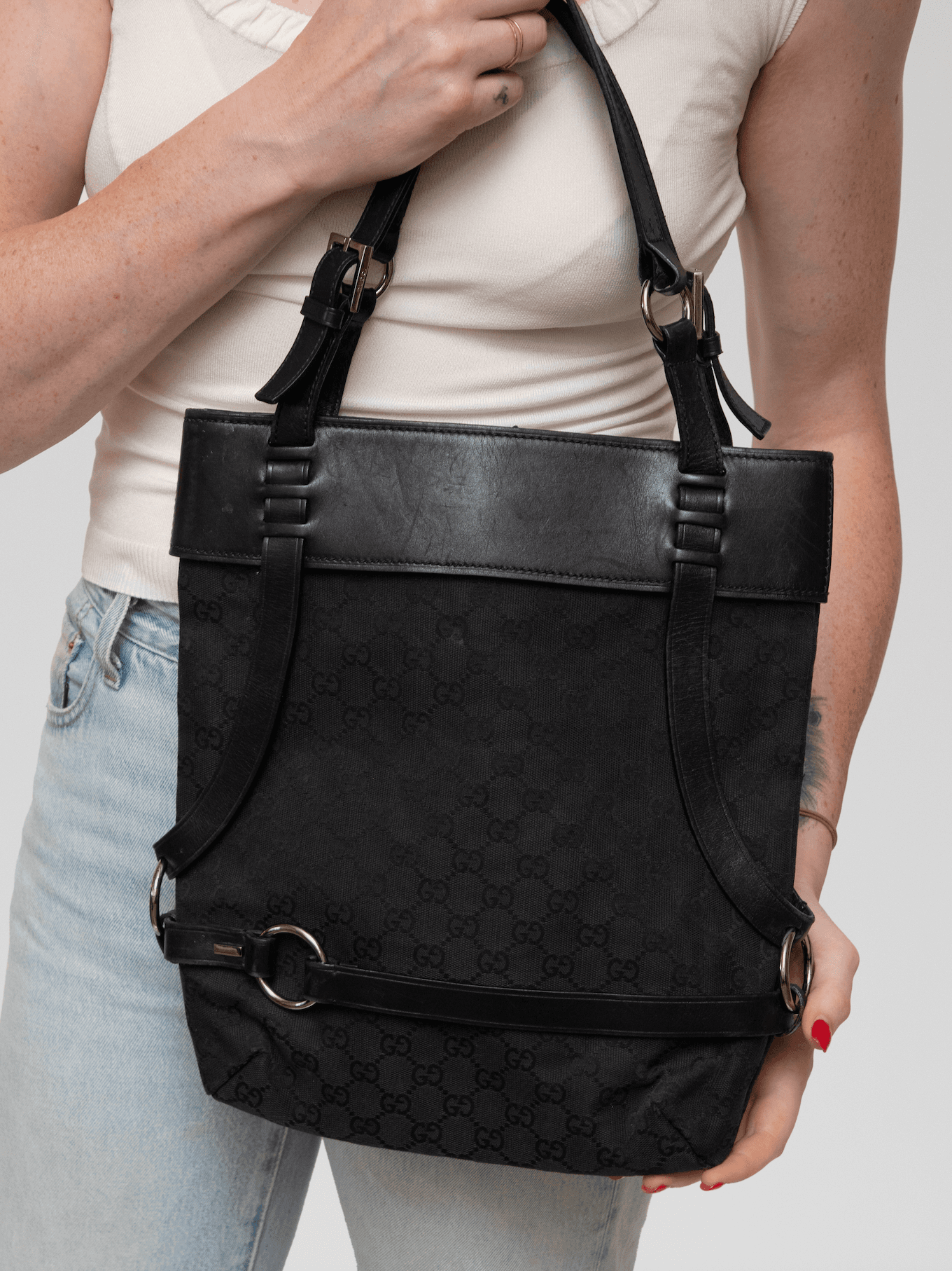 Rendered in understated black GG canvas with tonal leather accents, this structured Gucci shoulder bag is accented with distinctive harness-style straps and silver-tone ring hardware for a sleek, utilitarian aesthetic. - Image 1