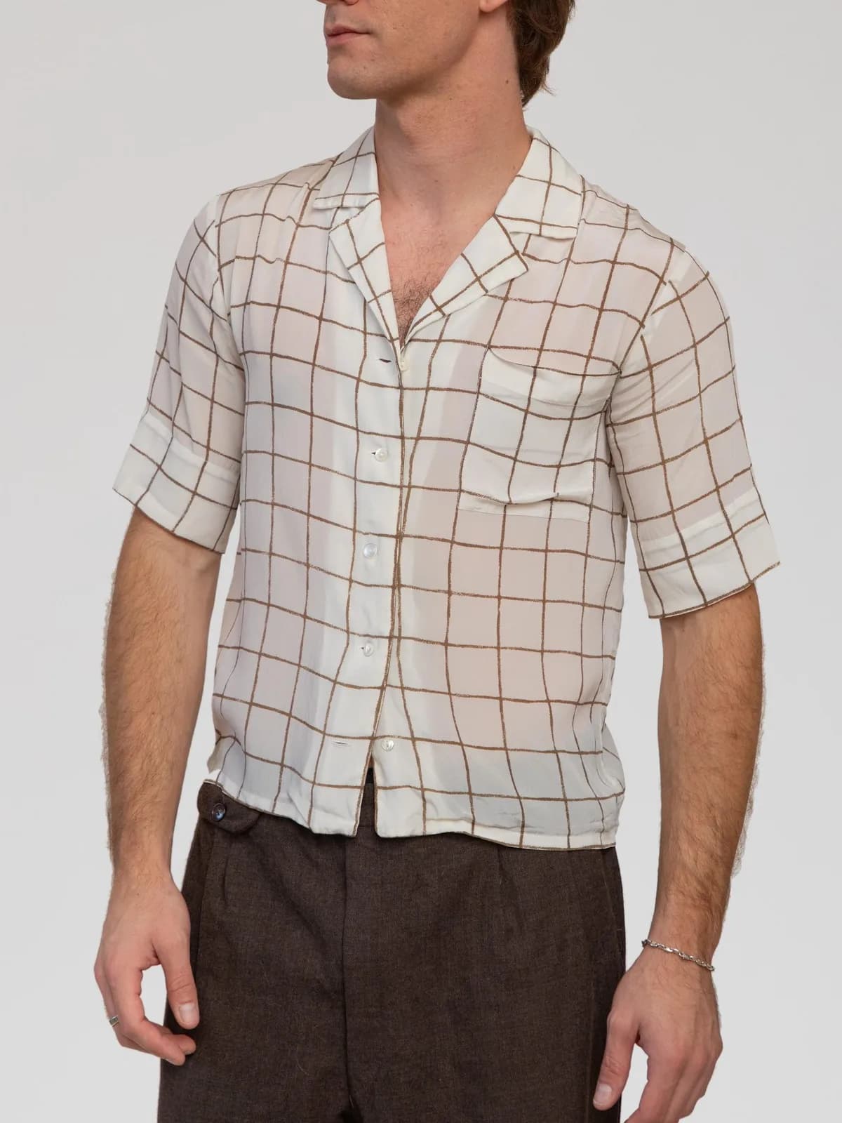 Vintage Christian Dior short-sleeve camp shirt in off-white featuring a brown windowpane grid check pattern. Crafted from lightweight, semi-sheer woven silk with an open relaxed collar, a front patch pocket at the chest, pearlized front buttons, and a straight hemline. - Image 1