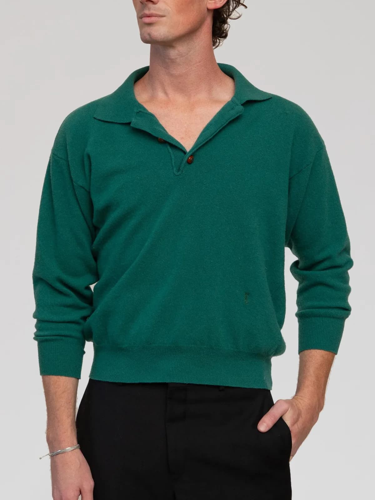 Vintage Yves Saint Laurent Pour Homme long-sleeve knit polo sweater in rich emerald green. Features a relaxed silhouette with dropped shoulders, a flat open collar, a two-button placket with tortoiseshell-style buttons, tonal embroidered logo detailing near the lower hem, and ribbed cuffs and hemline. - Image 1