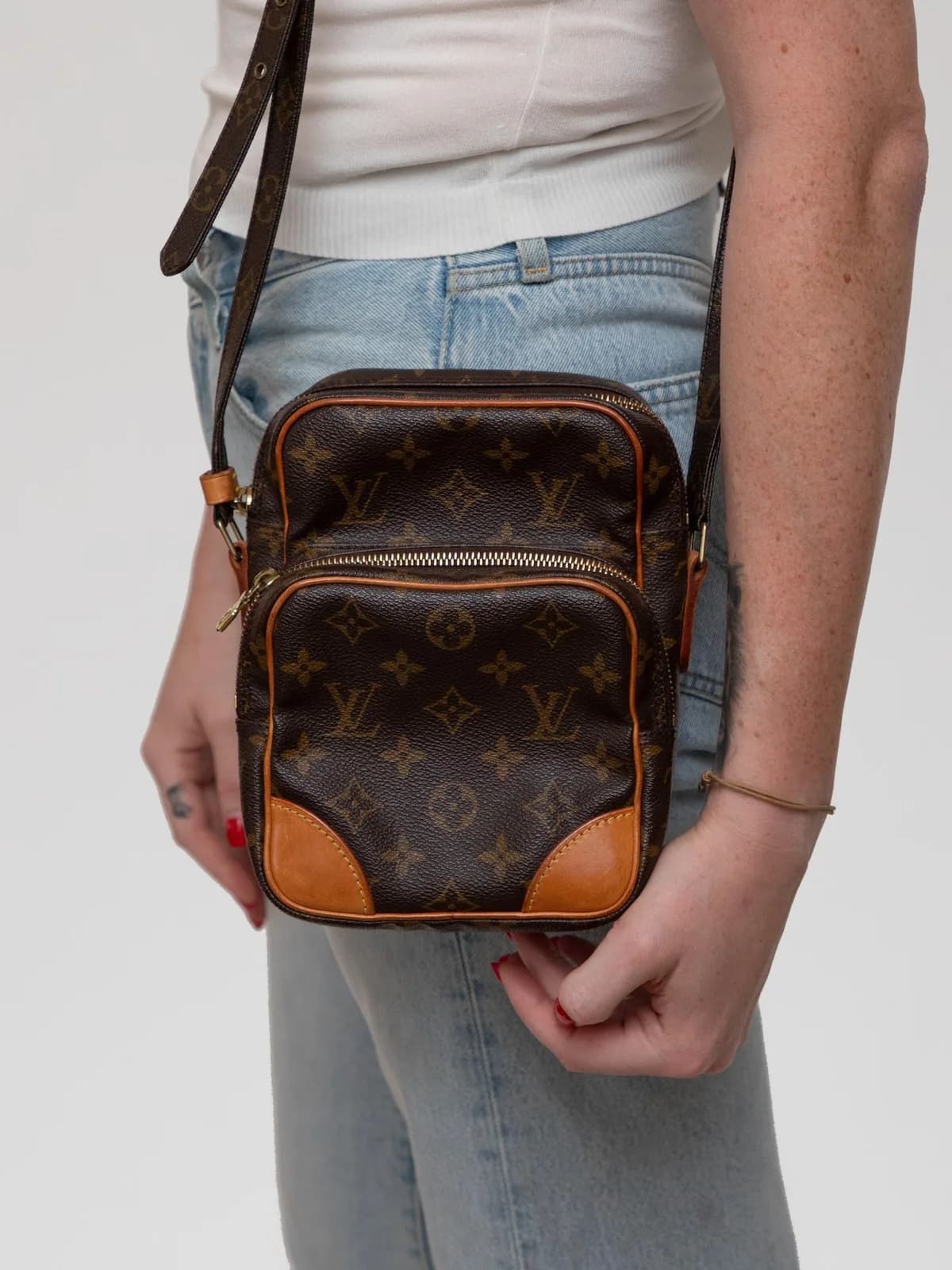 Rendered in signature Monogram canvas with warm Vachetta leather accents, this classic Louis Vuitton Amazon crossbody bag combines vintage utility with modern hands-free luxury. - Image 1