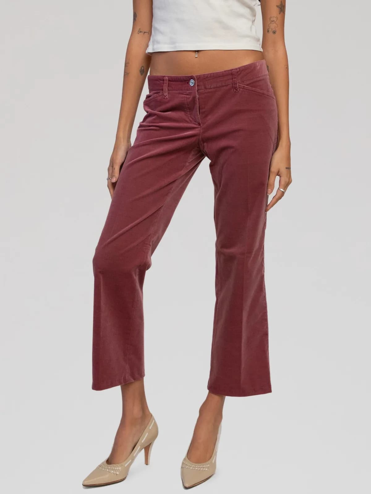 Dolce & Gabbana low-rise corduroy trousers crafted in a dusty rose-pink hue. Designed with a fitted, slightly flared silhouette, belt loops, front slit pockets, back patch pockets, and a zip fly with button closure. Features a signature leather back waistband patch with a gold-tone metal logo plate engraved with "DG". Made in Italy. - Image 1