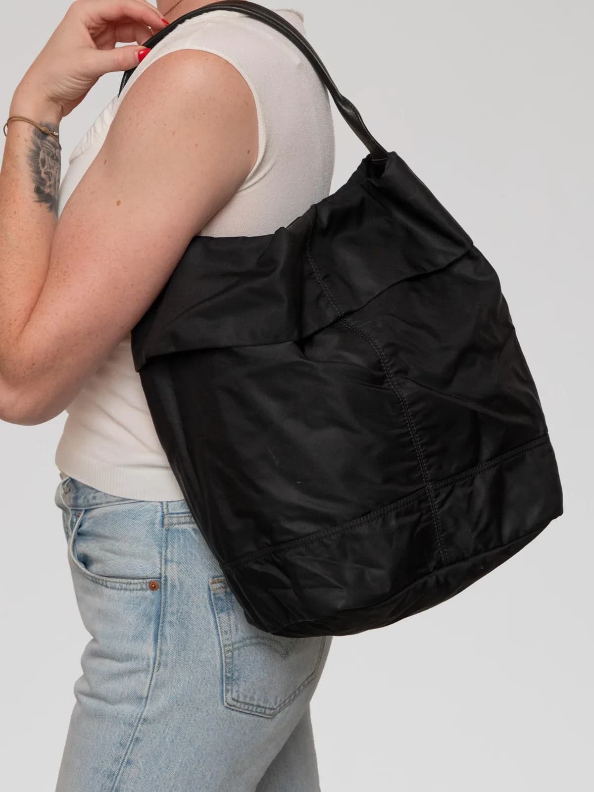 Crafted from sleek black technical nylon with a leather shoulder strap, this minimalist Moncler "à porter" shoulder bag pairs modern utilitarian ease with a spacious, lightweight hobo silhouette. - Image 1