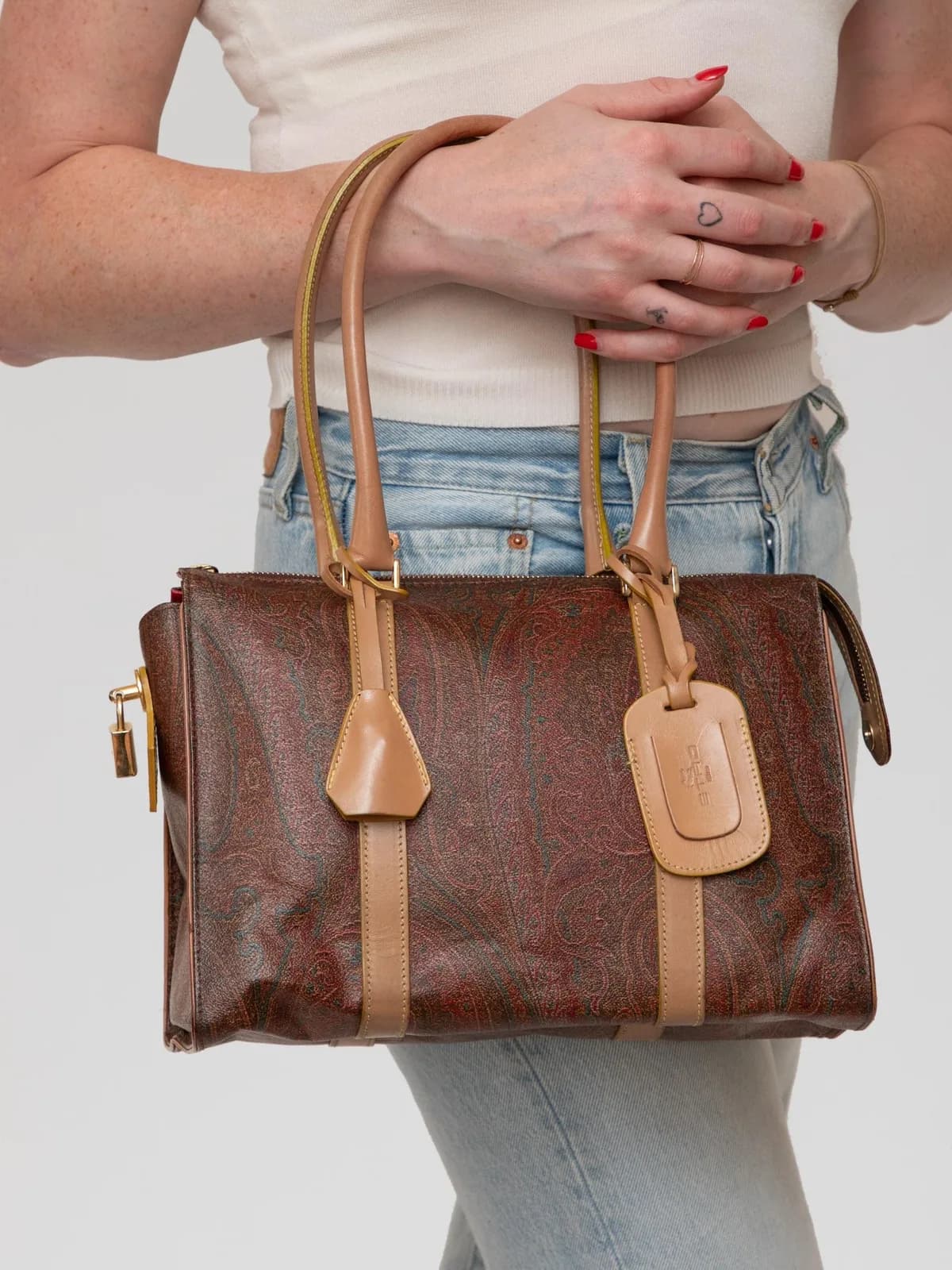 Showcasing Etro's iconic Paisley coated canvas, this vintage top-handle tote is trimmed with smooth natural leather handles, a matching leather luggage tag, side padlock detail, and a vibrant red interior lining. - Image 1