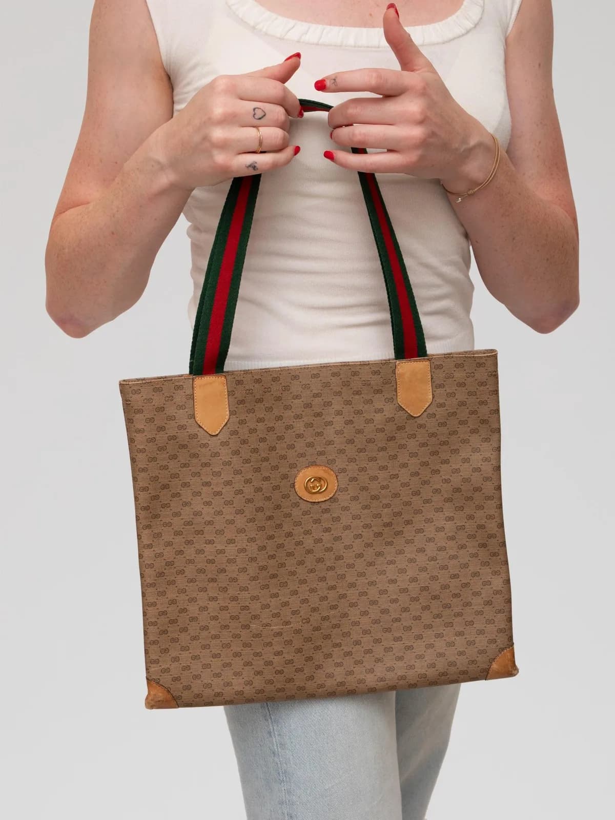 Showcasing classic micro-GG canvas framed in light tan leather, this vintage Gucci tote features signature red-and-green Web stripe handles and an interlocking GG crest plaque for an unmistakable mark of heritage luxury. - Image 1