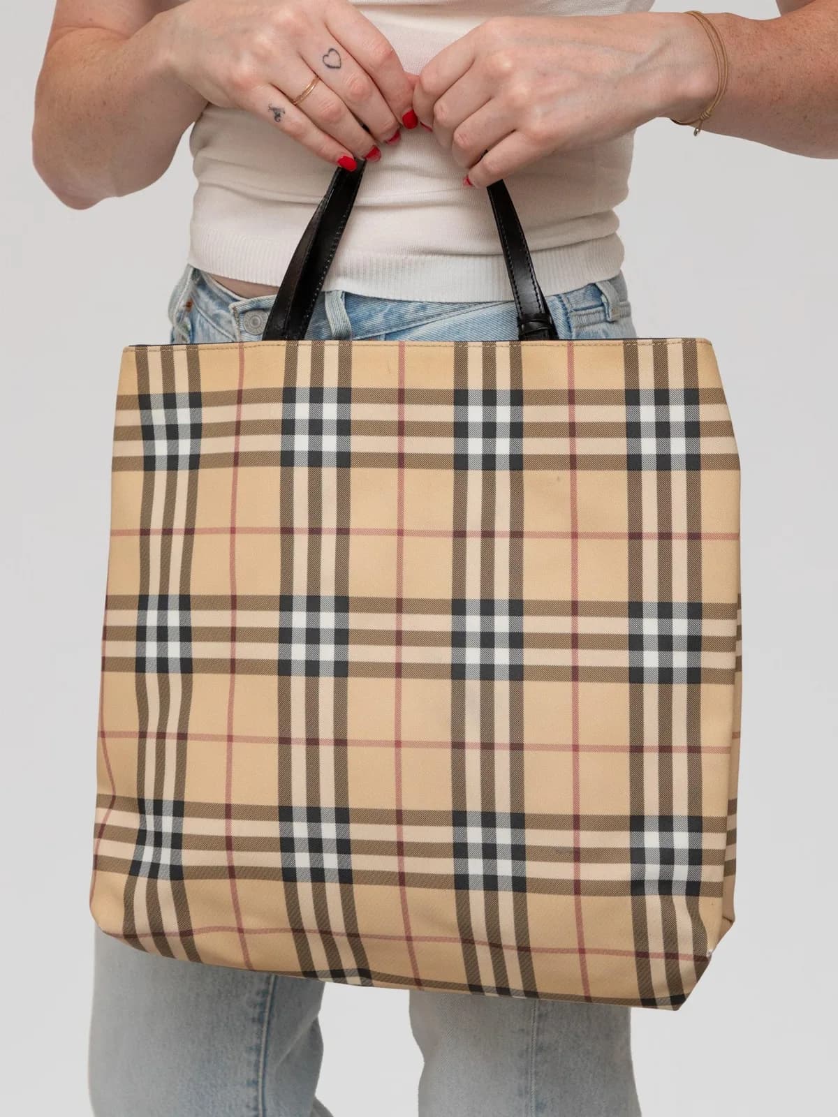 Showcasing the iconic beige House Check canvas paired with sleek black leather shoulder straps, this classic Burberry tote bag offers timeless British sophistication in an essential daily silhouette. - Image 1