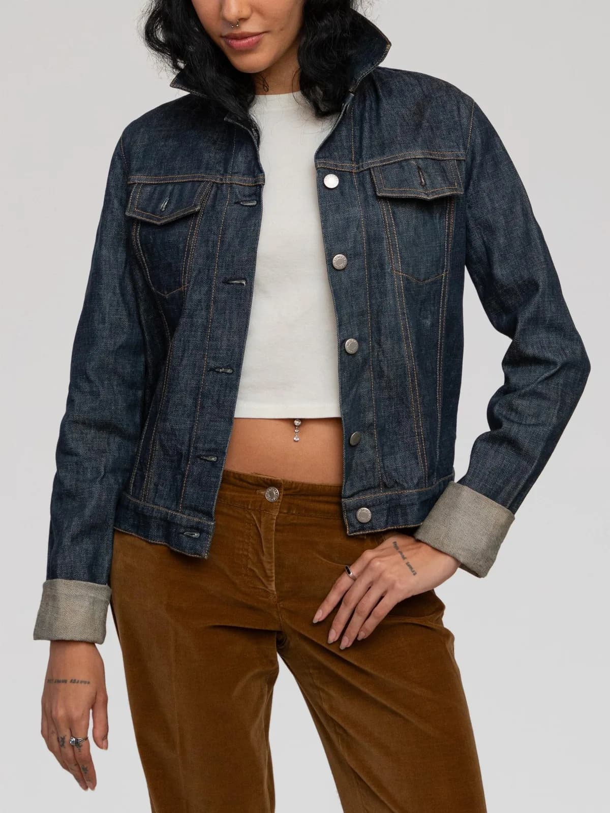 Vintage Helmut Lang "Classic Denim" jacket crafted from dark indigo raw cotton denim with contrast tobacco stitching. Features a structured trucker silhouette, point collar, front button closure with branded silver-tone metal hardware, two flap chest pockets, buttoned waist tabs, and signature back yoke stitch detailing. Made in Italy. - Image 1