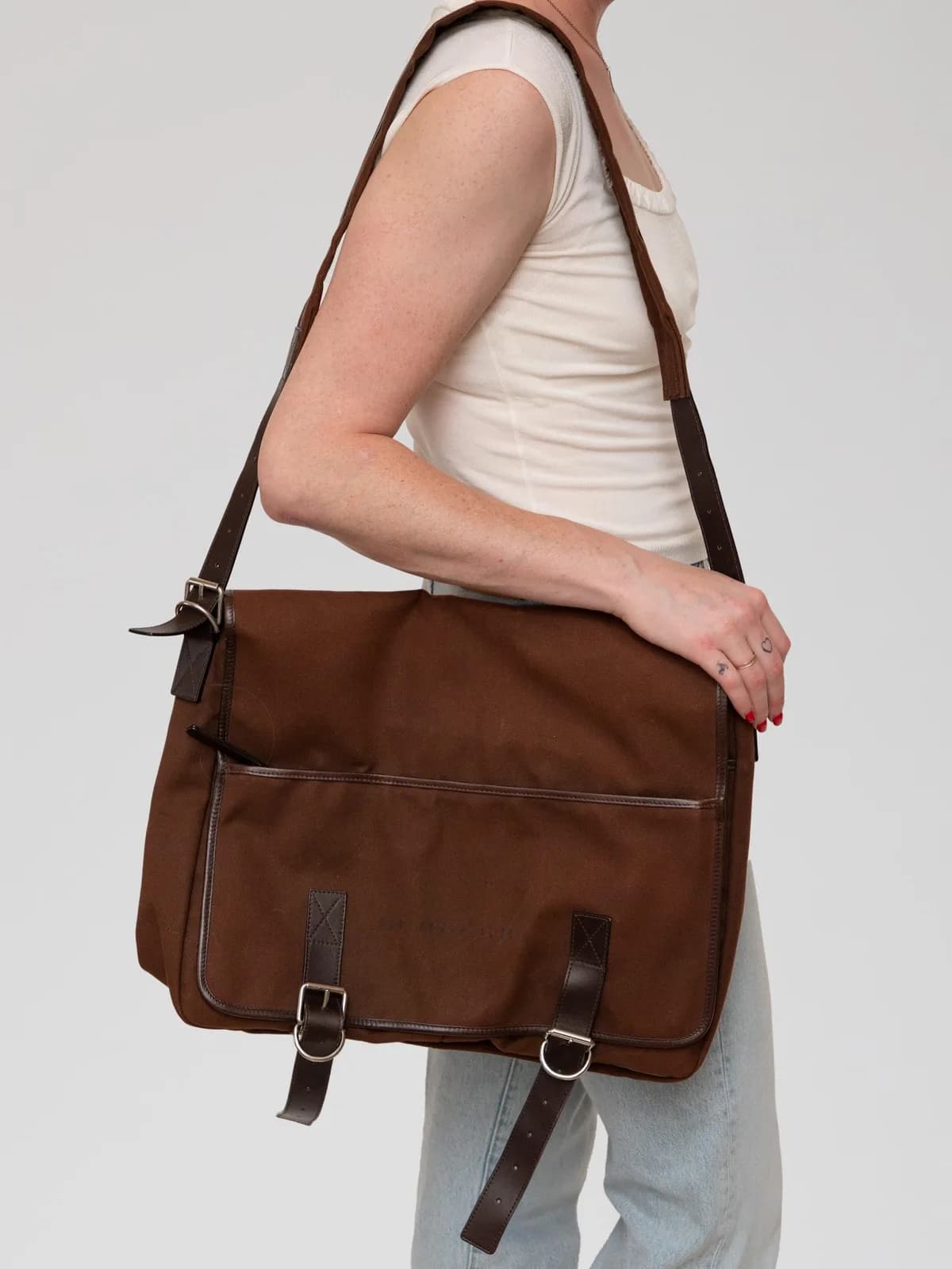 Crafted in rich chocolate brown canvas with tonal leather trims, this vintage Burberry messenger bag features dual buckle fastenings, an adjustable shoulder strap, and a subtle printed logo for an effortlessly stylish, collegiate appeal. - Image 1